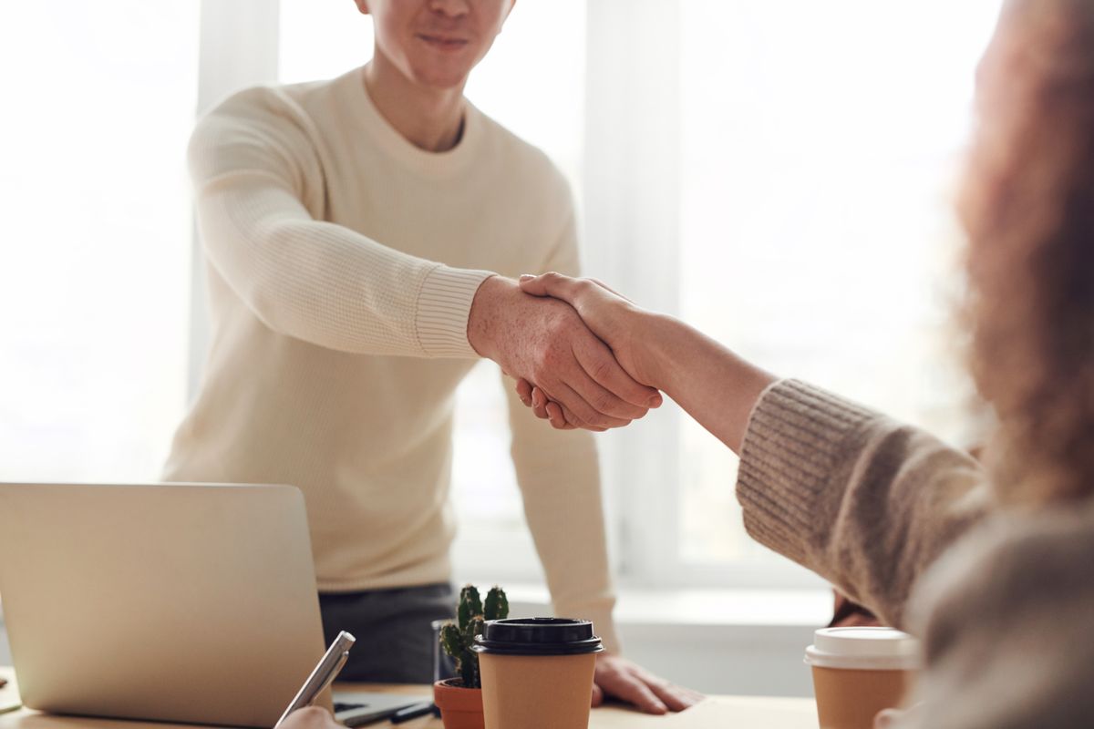 Colleagues shaking hands across a meeting table